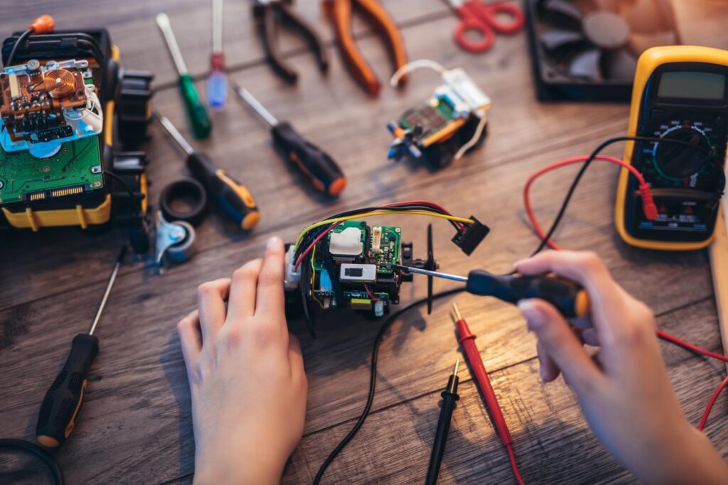 Kobieta majsterkuje w garażu, obok miernik prądu